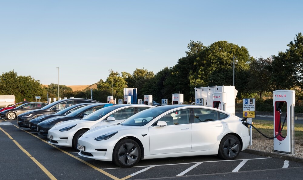 Tesla cars lined up near a quick charger